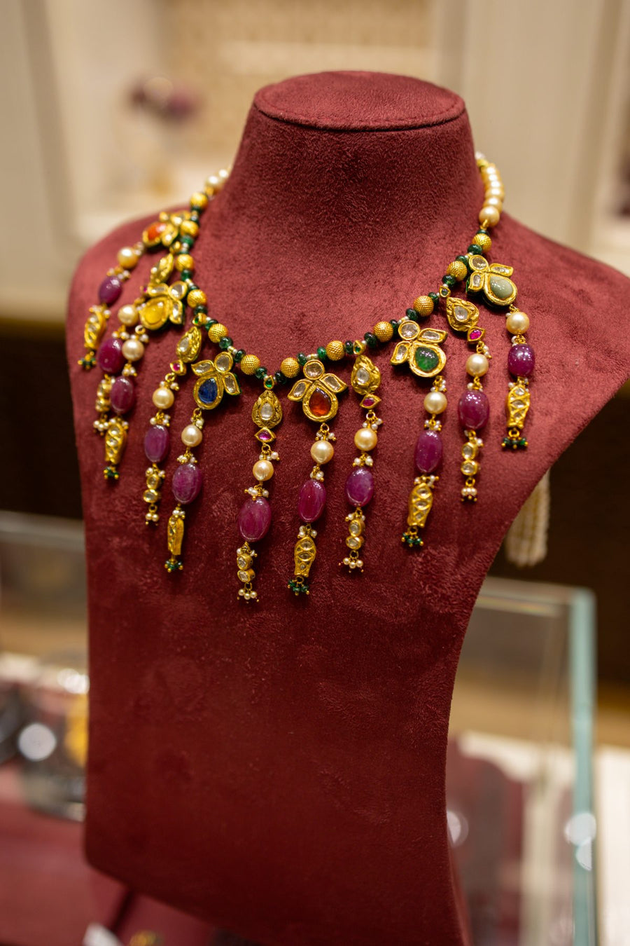 A necklace of polki and rubies on maroon velvet in the Raipur store