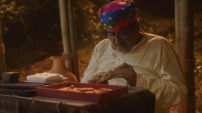 A master sonar in a turban turns a gold bangle in his hands